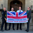 An Armed Forces Network banner and a AF Covenant banner frame PC Scott Caswell, DCC David Gardner, DCI Wayne Reynolds and DC Kath Linton holding the Armed Forces flag outside Woodcote House, LW HQ